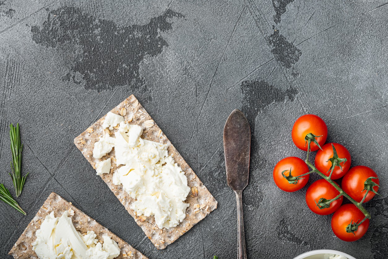 Curd sandwiches with fresh herbs. Crispbread toast with cottage cheese, on gray stone table background, top view flat lay, with copy space for text