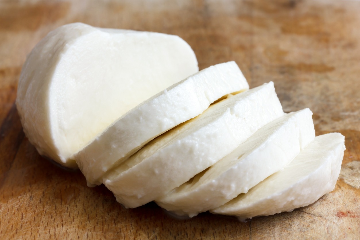 Single ball of mozzarella cheese sliced and isolated on rustice