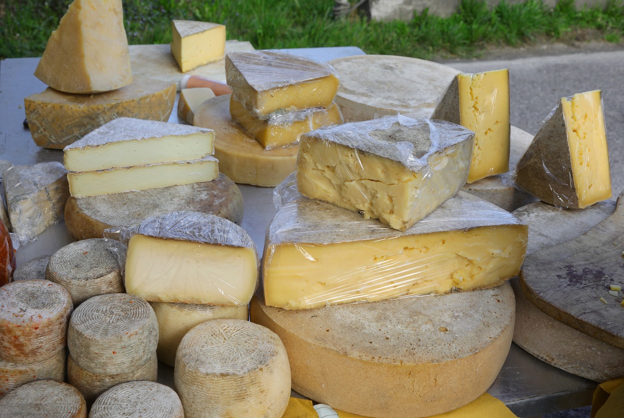 aged cheese wheels and fresh cheese chunks for sale at a stall