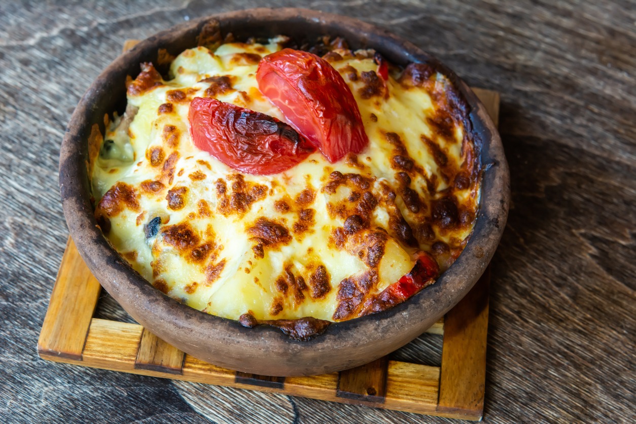 A clay pot containing a cheesy dish