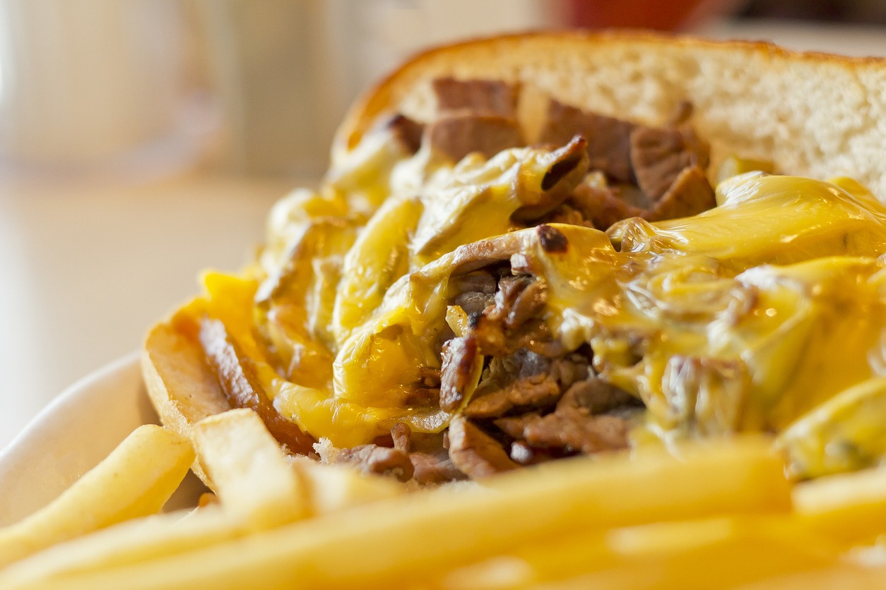 A Philly Cheesesteak with onions and peppers with fries on the side