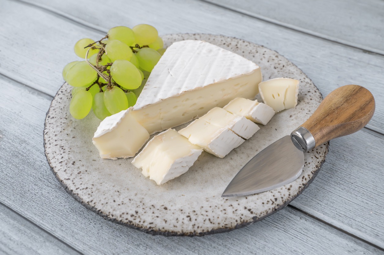 Camembert Brie cheese with grapes in a handmade clay craft plate
