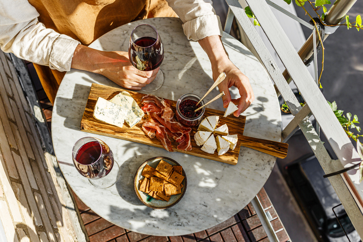 Varied appetizer Cheese board with soft cheese, fruit sauce and red wine on marble table