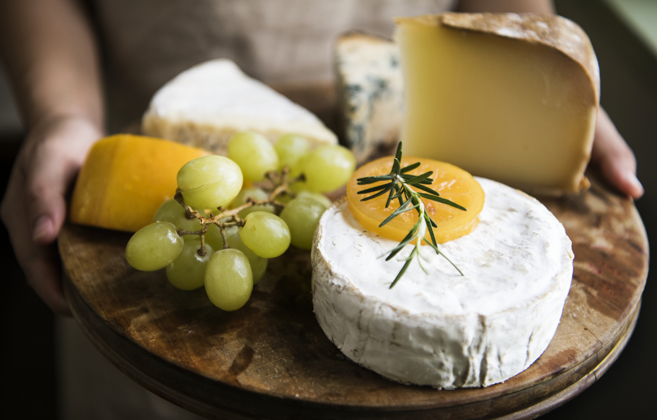 variation of cheese and green grapes on a wooden platter