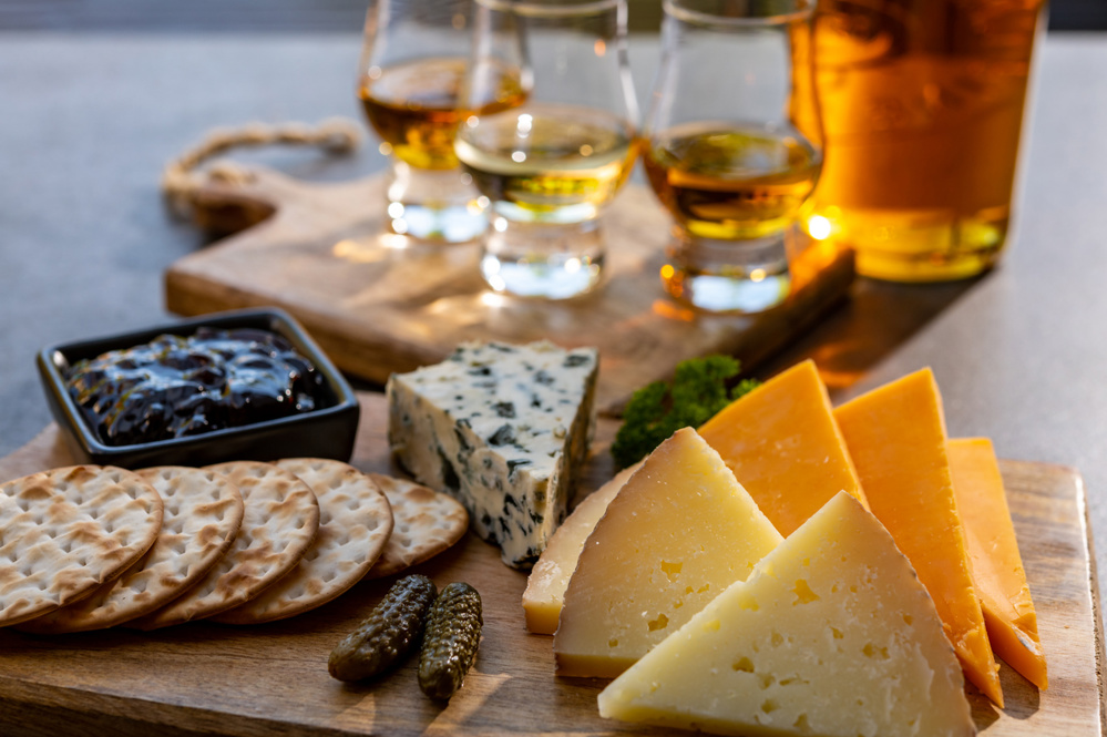 Whiskey and cheese pairing, tasting whisky glasses and plate with sliced cheeses