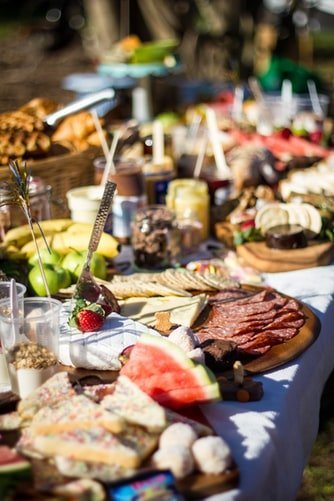 a buffet table filled with different kinds of cheese, meat, crackers, and fruits