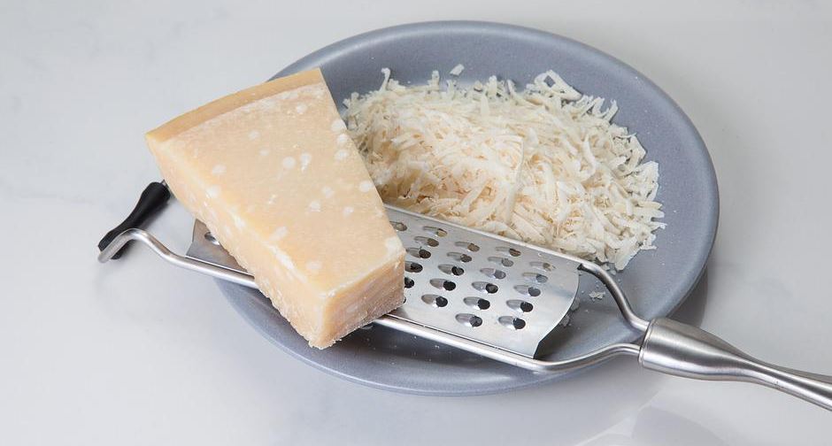 a slice of and grated parmesan cheese on a plate, grater