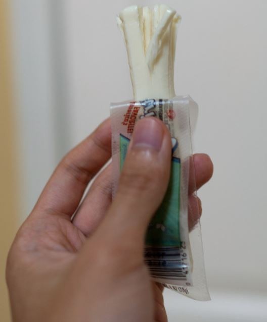 close up of a person’s hand holding an American string cheese